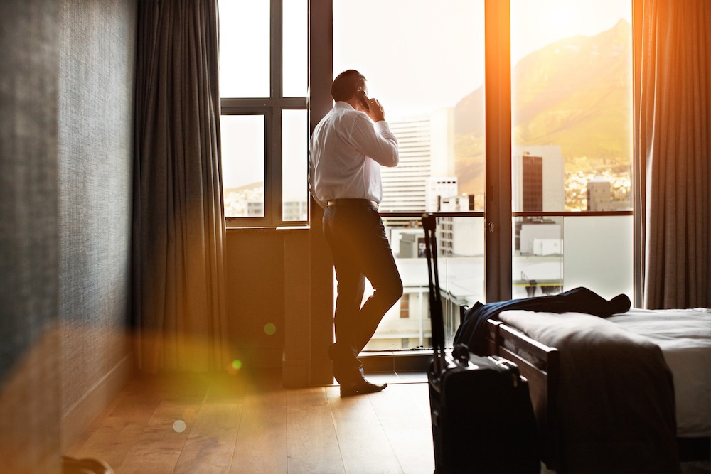 Man in hotel room on cell phone talking to his counselor